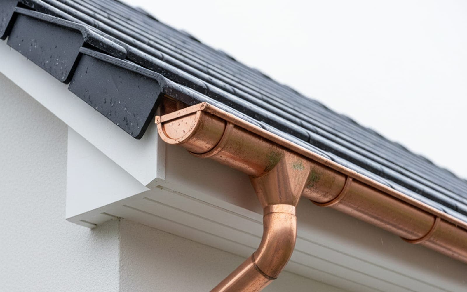 Neue Kupfer-Dachrinne an einer modernen Putzfassade – kupferrote Oberfläche mit beginnender Patina.